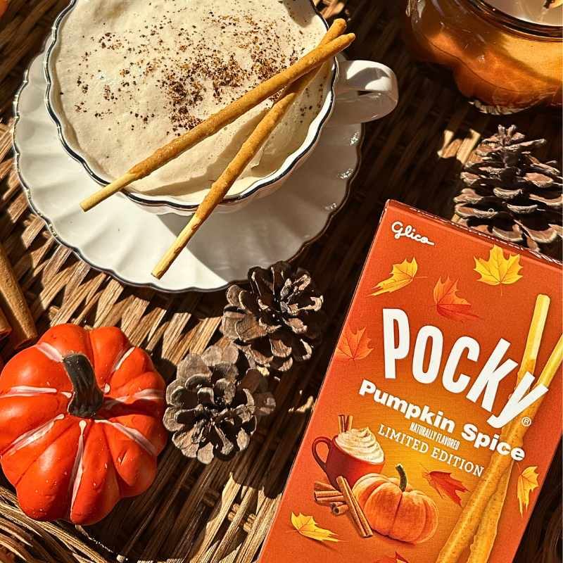 A box of Pocky Pumpkin Spice next to a cup of hot coffee with cream and Pocky Pumpkin Spice sticks.